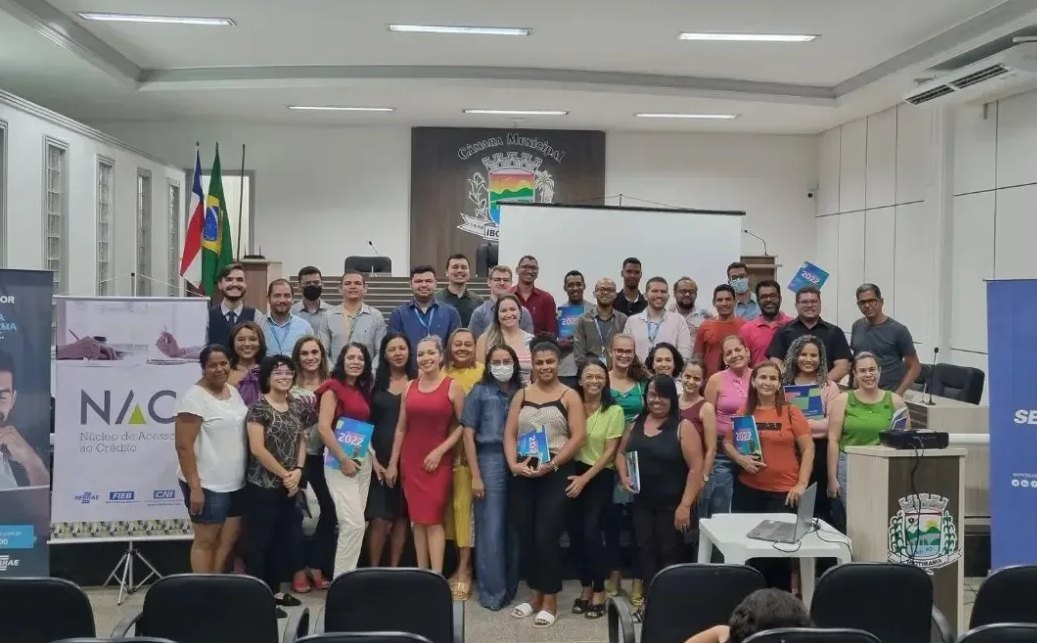 Foto de grupo com empresários e parceiros diante do banner do Núcleo de Acesso ao Crédito