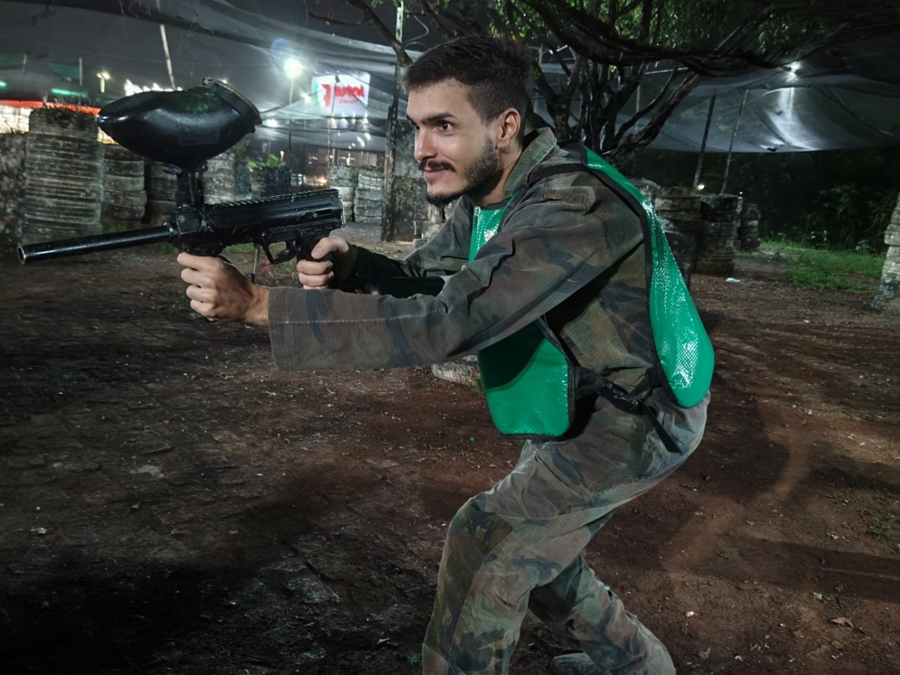 Matheus Ché em ação no paintball, com marcador e roupa camuflada