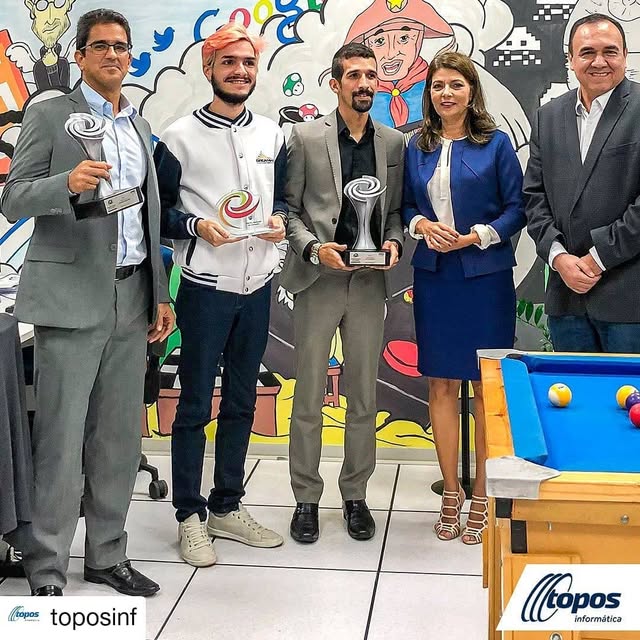 Matheus Ché segurando um troféu ao lado de outros premiados