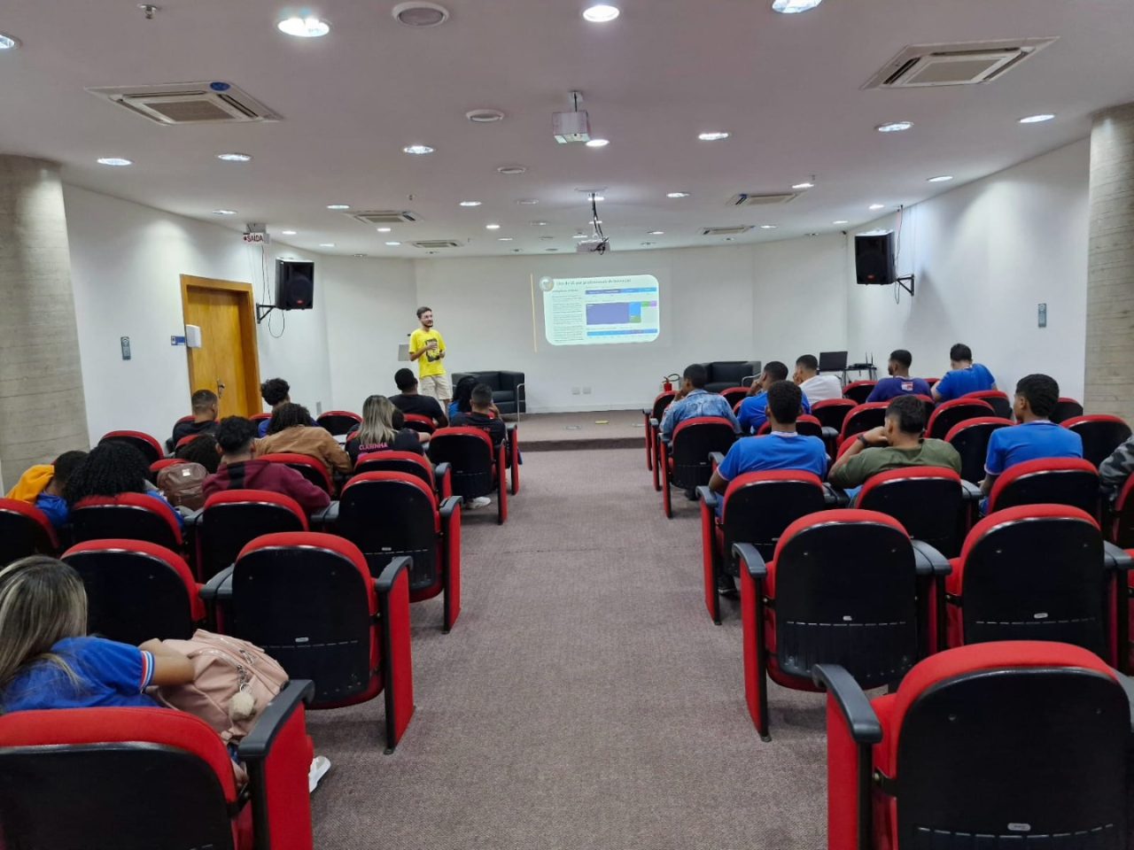 Auditório com estudantes assistindo a uma palestra